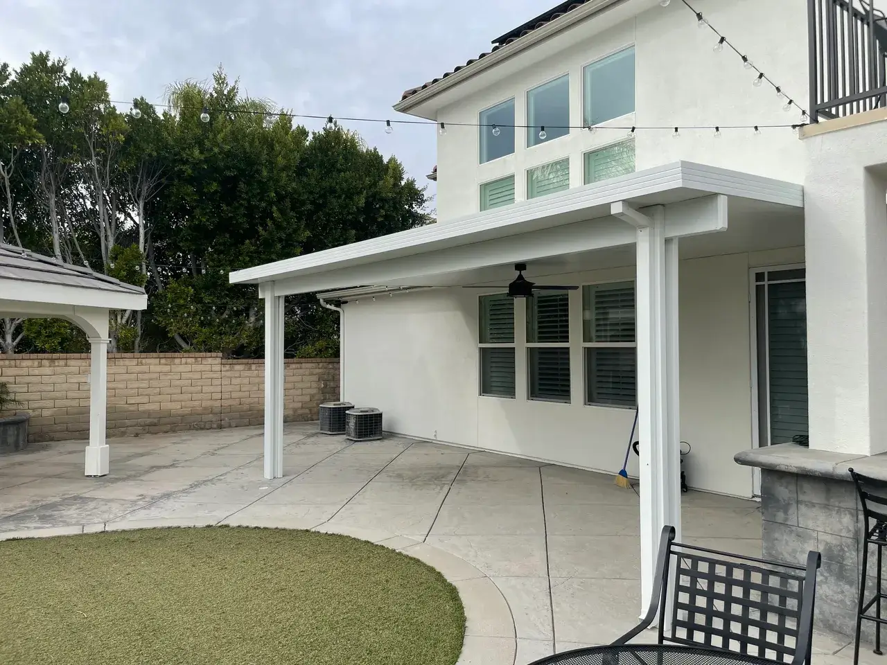 Modern patio with white pergola and chairs.