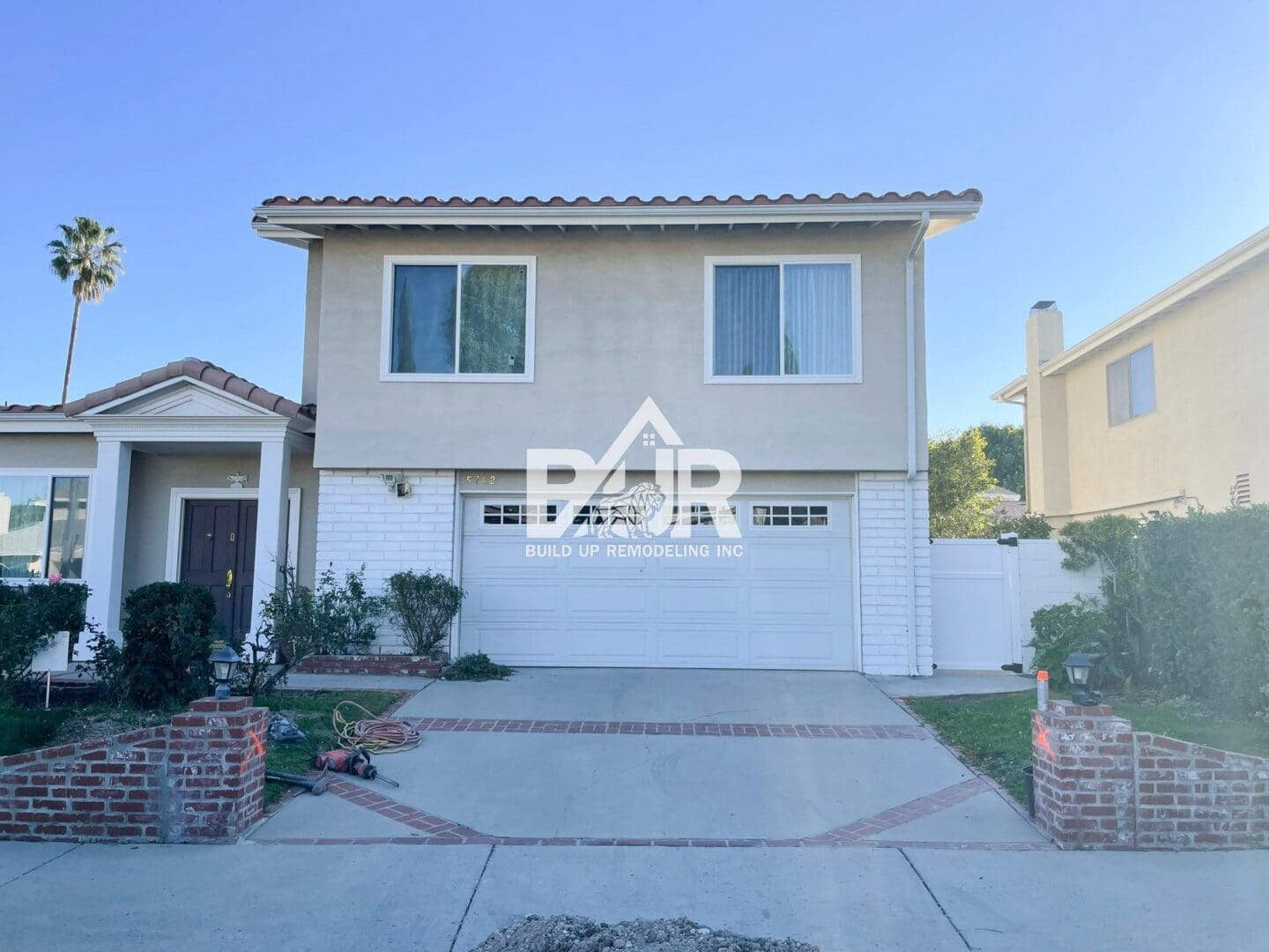 Two-story suburban house with a double garage and clear blue sky.