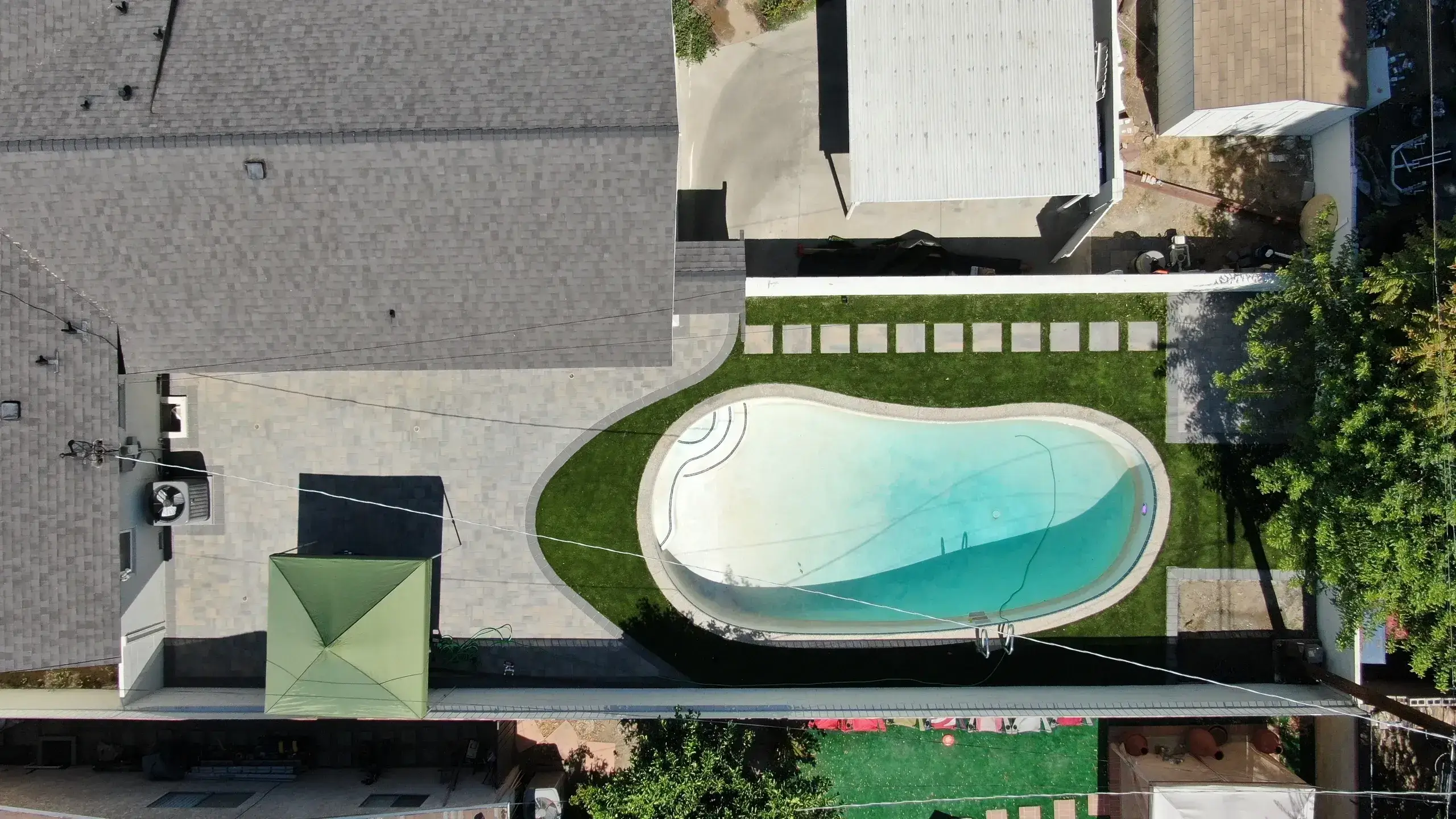Aerial view of a kidney-shaped swimming pool in a backyard.