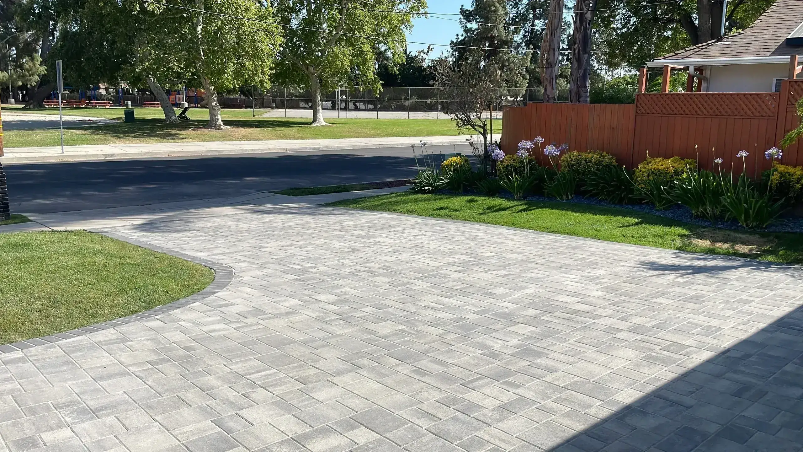 A paved driveway with surrounding green grass and trees in the background.